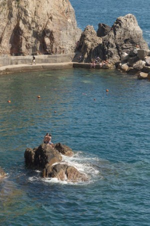 couple sitting on rock in blue water